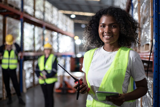 Outside of logistics retail warehouse. Beautiful African American manager using tablet computer for inventory. Delivery service with walkie talkie.