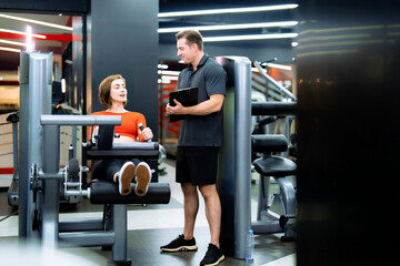 Caucasian woman exercising at gym with trainer.