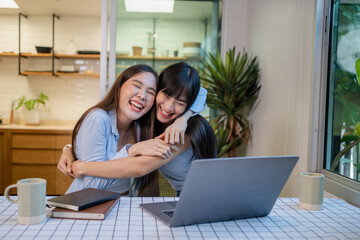 Cheerful girlfriends in had near face smiling while planning further work together and using laptop at home.