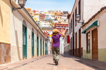 Fototapeta premium Woman on vacation walking through the city of San Sebastian de la Gomera next to the Iglesia De La Asuncion, Canary Islands