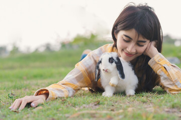 White rabbit survey on green grass floor with owner eye of love and care , beautiful and cute moment with woman and animal.