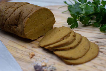 Vegan seitan gluten meat, rolled, steamed and sliced, wooden board.