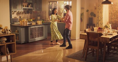 Young Couple Dancing and Having Fun in the Kitchen: Enjoying Each Other's Company and Playfully Moving to Music. With Joyful Laughter and Smiles, they Embrace the Music and Dance. Wide shot