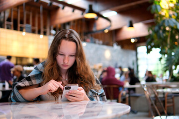 Attractive Woman typing text message on smart phone in a cafe with a coffee. High quality photo