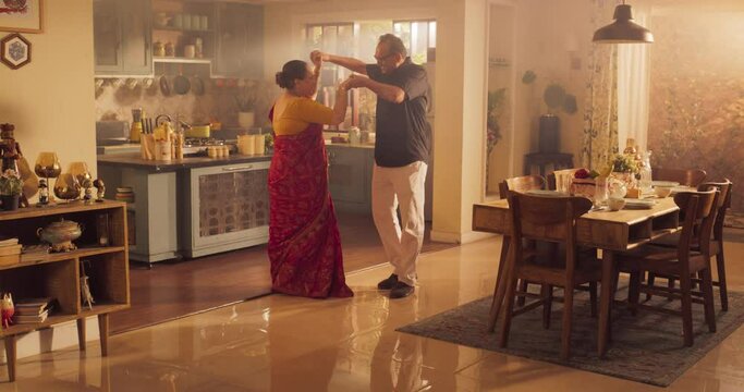 Elderly Couple Dancing  Kitchen and Enjoying Each Other's Company: Moving to the Rhythm of Music  and Love, With Smiling Faces and Loving Embrace, Celebrate Anniversary. Slow Motion Wide