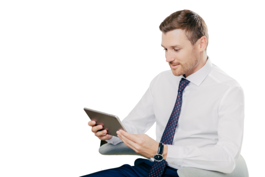 Concentrated sideways shot of businessman in formal clothes holds modern tablet computer, checks data or email box, connected to wireless internet, sits in modern spacious cabinet. Business concept