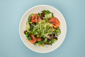 Portion of fresh gourmet salad with salmon on blue background