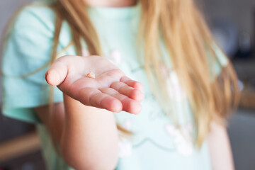 Little girl's hand holding and showing her fallen milk front tooth close up.