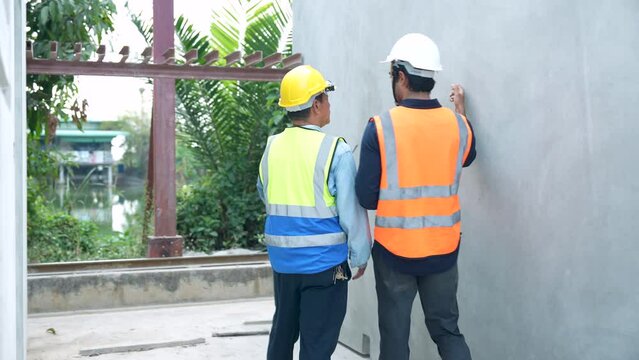 Team of construction engineers or contractors discuss job details and view construction progress at the production site.