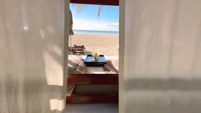 Luxury beach cabana with tropical drinks, sand and the ocean in the distance