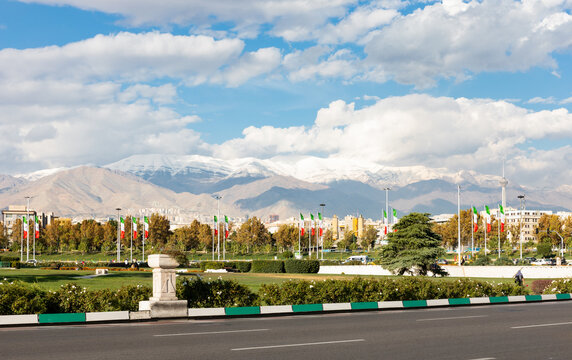 View of Azadi Square with Iranian national flags flying and Alborz mountains on background, Tehran, Iran.