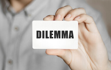Card with text dilemma in a man's hand