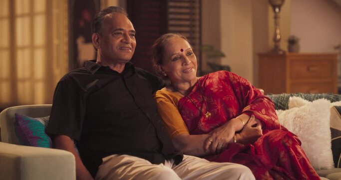 Blessed Love: Elderly Couple Enjoying a Quiet Evening at Home, Watching a Heartfelt Movie on TV. Beautiful Indian Husband and Wife watching Favourite Streaming Service TV Shows Cozy Living Room 