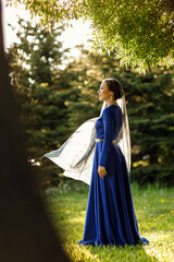 a girl in a blue dress in a spring forest