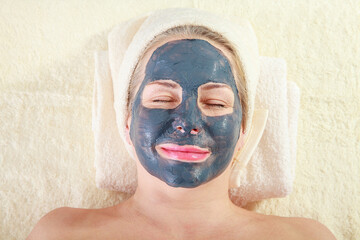 Revitalizing Self-Care: Woman Enjoying a Spa Day with a Clay Facial Mask. Close-up of a stunning middle-aged woman pampering herself with a rejuvenating treatment.