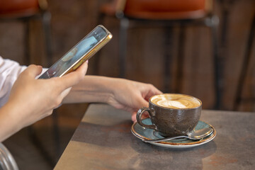 Young girl using Photography of smartphone of latte art coffee on mobile camera display while shooting.