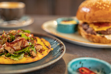 burger and kebab on bread with sauces served on the table in the restaurant