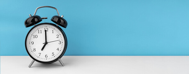 Black alarm clock on blue background
