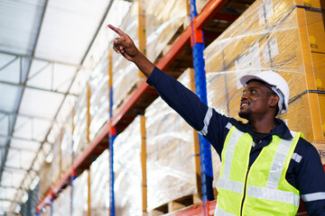 Portrait of smart and good looking African ethnicity warehouse worker standing between the roll of inventory shelf.