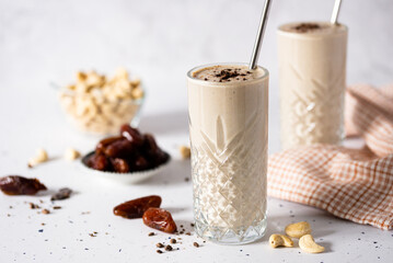 Glass full of a Creamy Cashew Smoothie Infused with Sweet Dates Delight, healthy, creamy, white and plant based for vegan people - obrazy, fototapety, plakaty