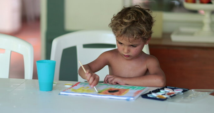 Young boy painting at home. Child crafting using aquarelle paint, kid doing artistic homework drawing