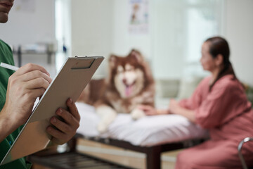 Vet taking notes in document after examining Samoyed dog