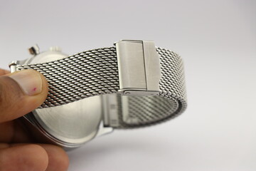 Watch strap made from stainless steel links that is adjustable held in the hand on a white...