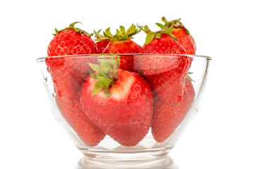 Several red sweet strawberries in a glass dish, macro, isolated on a white background.