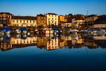 Fototapeta na wymiar Custom House Quay in Falmouth at sunrise with gorgeous water reflections. 