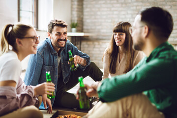 Group of happy friends having fun at home while drinking beer