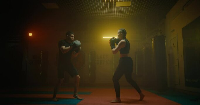 woman training in fight club, practicing hand punches with man coach, sport activity, 4K, Prores