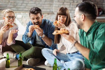 Young happy friends having fun while eating pizza