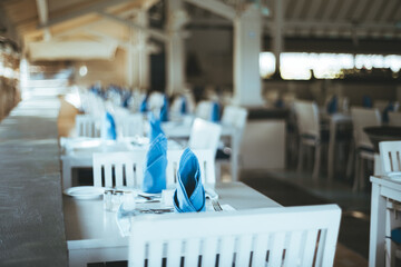 Maldives; selective focus on a table with blue decoratively folded napkins, silverware, and a fancy sous plat, drawing attention to the table setting, highlighting its elegance and attention to detail