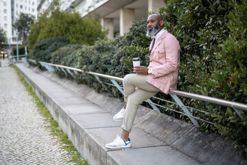 Lisbon; A black man with a bald head, wearing a pink jacket and a full-grown beard with white hair,...