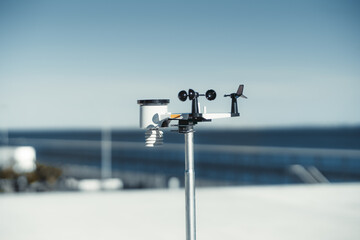 A sleek wireless weather station made in a metallic material has some black and white spots and provides accurate weather information against a dreamy defocused blue skies