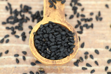 Black cumin seeds and essential oil with bowl and wooden shovel or spoon. Nigella Sativa in glass bottle. Organic herbal medicine for many diseases
