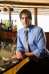 Hispanic mid adult man leaning on bar with martini looking at viewer.