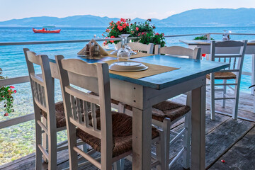 A Captivating View of an Empty Tavern Restaurant by the Picturesque Seafront, Featuring Inviting Wooden Chairs and Tables