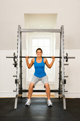 Fototapeta premium Woman lifting weights in gym smiling.