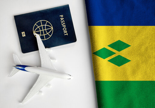Flag of Saint Vincent and the Grenadines with passport and toy airplane. Flight travel concept
