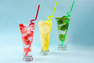 Three glasses of chilled drinks on a blue background, lemonade, watermelon lemonade, mint lemonade, iced drinks