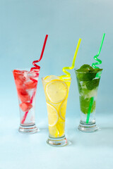 Three glasses of chilled drinks on a blue background, lemonade, watermelon lemonade, mint lemonade, iced drinks
