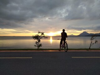 Fototapeta na wymiar ciclista observando o pôr do sol na lagoa