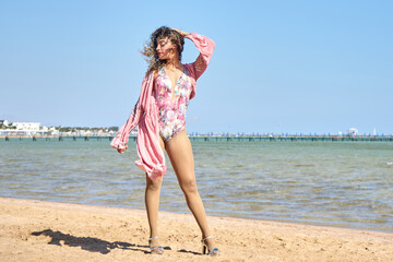 Close up summer fashion image of stunning sexy woman, posing on beach, wearing luxury stylish silk blouse and bikini, vacation glamour style              