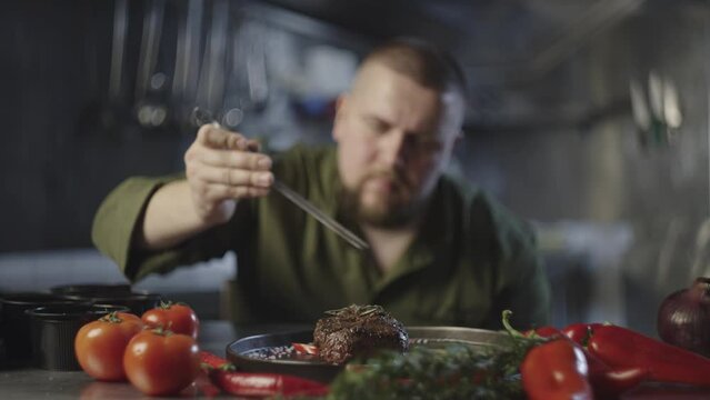 A professional chef prepares a meal in the restaurant kitchen. Serving and decorating the stack by a professional. Delicious and fresh products. High quality 4k footage