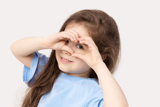 Portrait of positive child girl showing heart sign smiling isolated white background.