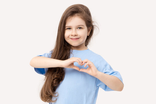 Portrait of positive child girl showing heart sign smiling isolated white background.