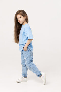 Full-length portrait of positive child girl sin a blue T-shirt and blue jeans isolated on white background.