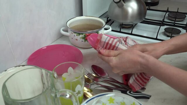 Woman hands with dry towel wipe dishes in surface table close-up. Housewife makes clean of washed plate napkin. Housekeep cleaning household chores kitchen utensile. Maid wipe wet dishware at home.