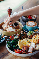 Morning breakfast on a table, waffles with cream, berries, coffee, cappuccino, bowl, omlet with vegetables, bread with butter, avocado cream, vegan food, healthy food, meal. - obrazy, fototapety, plakaty